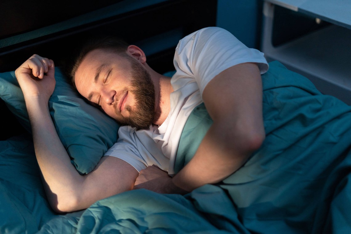 Mann genießt im Bett die angenehme Raumtemperatur trotz Sonne